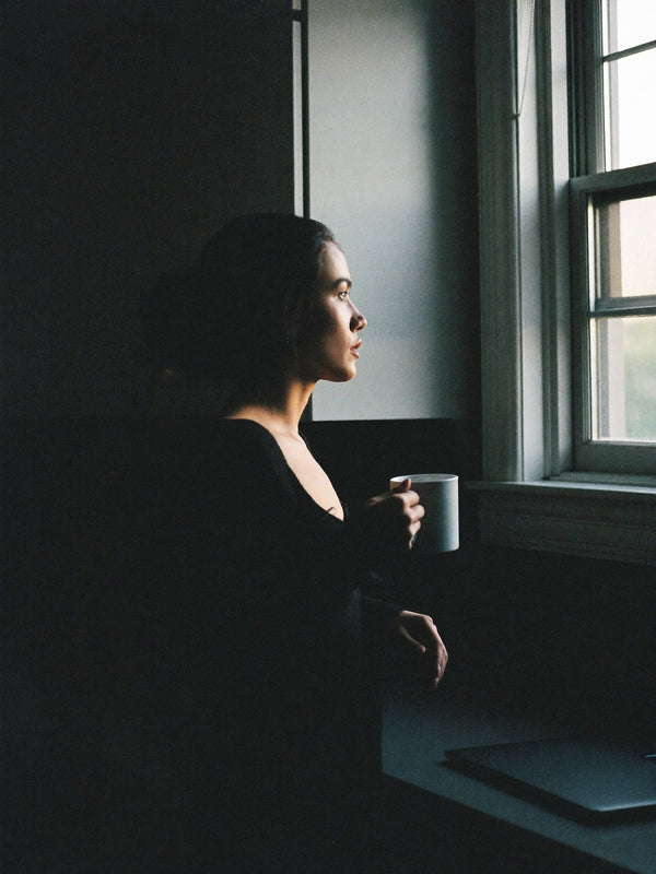 Woman holding a mug in early morning window light