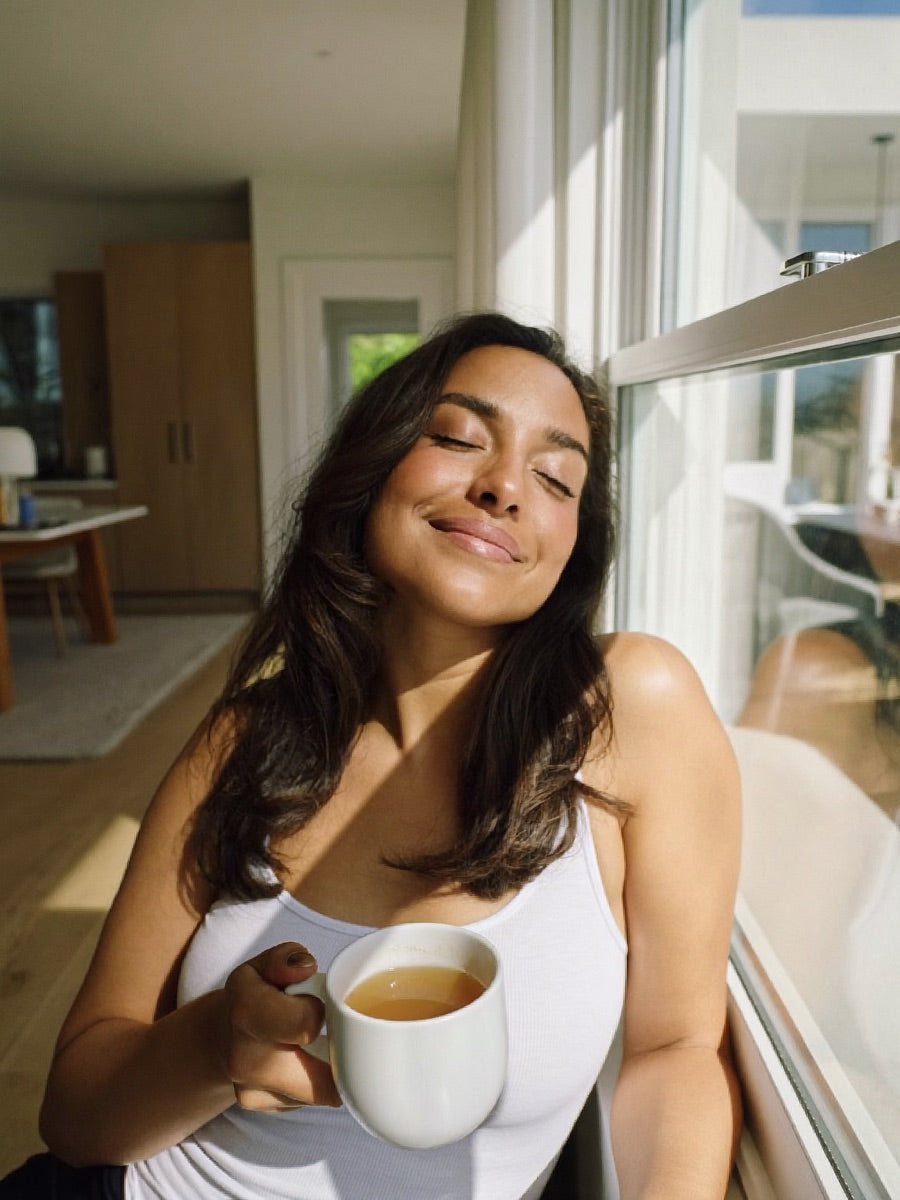 Woman pausing calmly with tea by a window