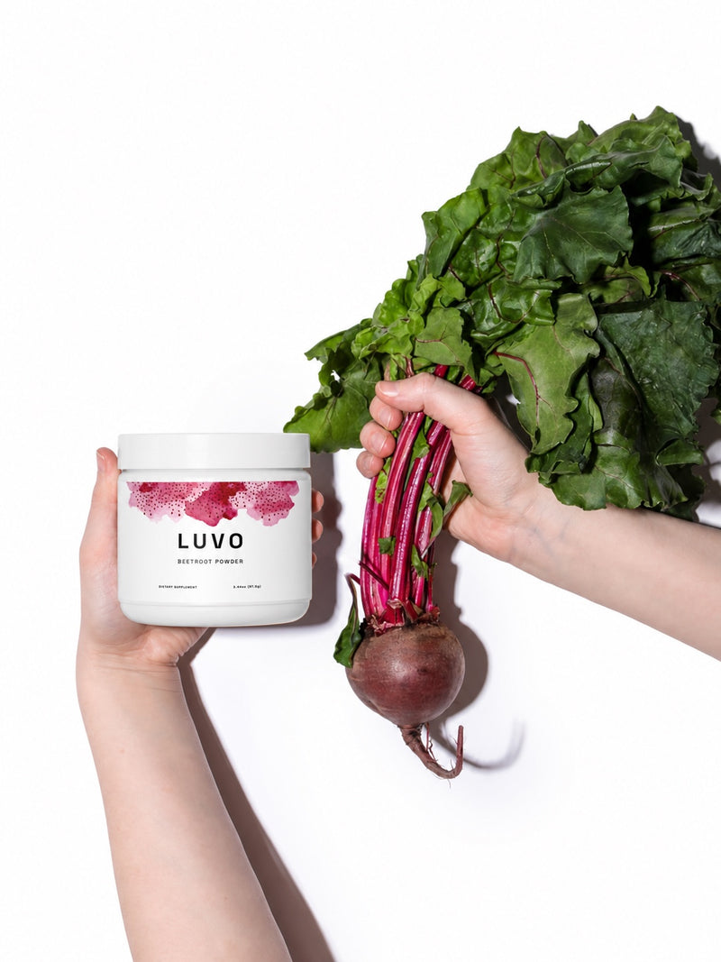 Hands holding a LUVO beetroot powder jar beside a whole fresh beet